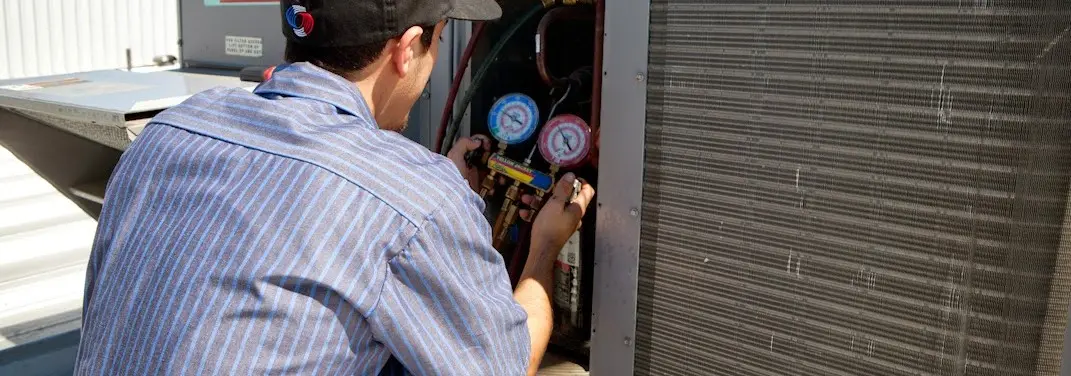HVAC technician servicing a condenser unit in West Springfield Town